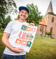 Ein Mann steht mit einem Plakat vor einer Kirche 