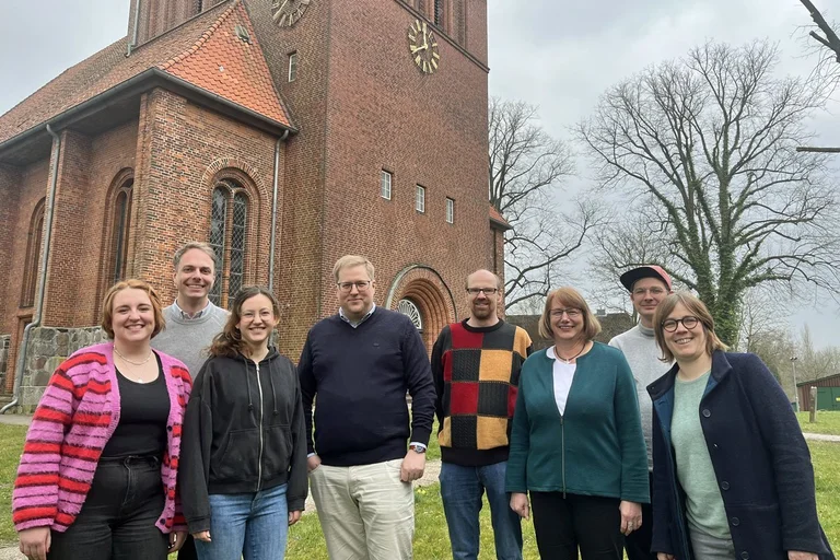 Eine Gruppe Frauen und Männer steht vor einer Kirche