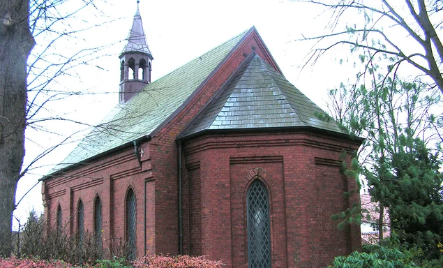 Die Süd-West-Ansicht der Friedhofskapelle Berkenthin, umgeben von Bäumen und Pflanzen