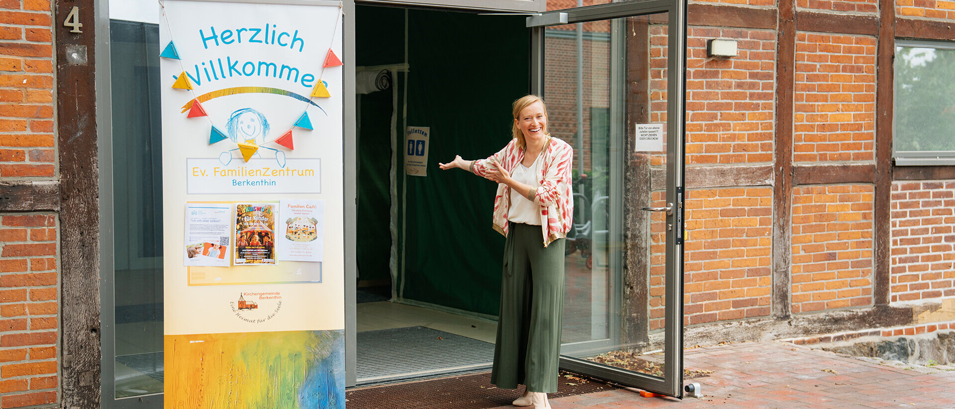 Eine Frau steht vor einer offenen Glastür und wei